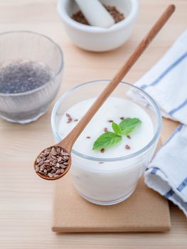 Nutritious flax seeds with glass of greek yogurt and wooden spoon for diet  meal setup on wooden background . shallow depth of field.