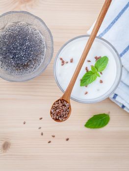 Nutritious flax seeds with glass of greek yogurt and wooden spoon for diet  meal setup on wooden background . shallow depth of field.