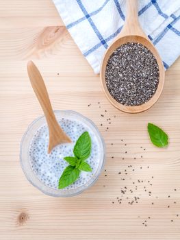 Nutritious chia seeds in glass bowl with wooden spoon for diet food ingredients setup on wooden background . shallow depth of field.