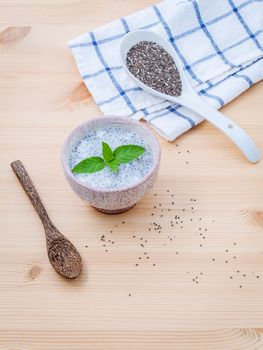 Nutritious chia seeds in glass bowl with wooden spoon for diet food ingredients setup on wooden background . shallow depth of field.