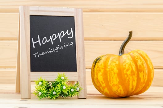Happy Thanksgiving - white chalk handwriting with pumpkins in wood room.