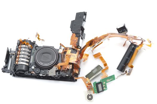 One disassembled digital camera with exposed lens and green soldered board against a white background
