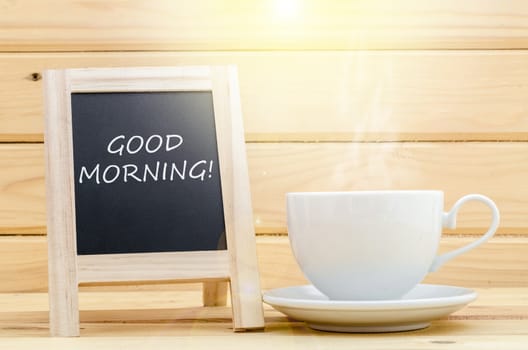 Cup of coffee with blackboard on vintage wooden background