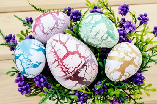 decorated easter eggs in the flower vase on wooden background.
