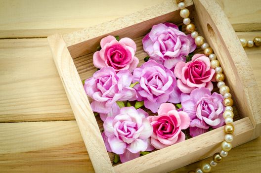 Vintage pink rose and Pearl Necklace on wooden background. Love concept.