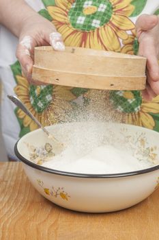 Women's hands preparing flour before baking pie.