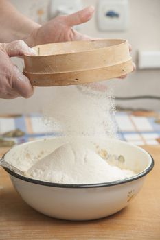 Women's hands preparing flour before baking pie.