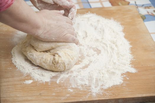 Women's hands preparing fresh yeast dough on wooden table