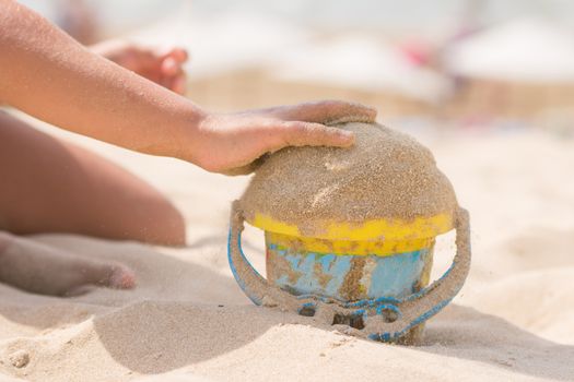 Childrens pen in the bucket pours sand on the beach