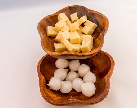 Cheese and Pickled Onion in wooden bowls on a white background.