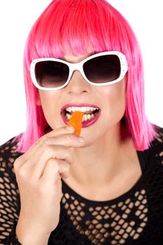 woman with pink hair eating raw vegetable