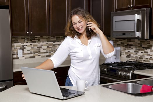 woman drinking coffee while chatting on the phone, using laptop