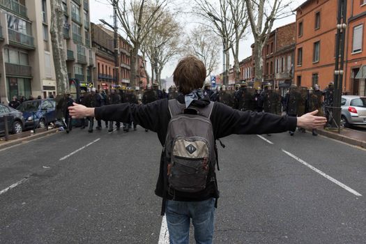 FRANCE, Toulouse:  A young protester faces French riot police officers during a demonstration against the French government's planned labour law reforms on March 31, 2016 in Toulouse, southern France. France faced fresh protests over labour reforms just a day after the beleaguered government of President Francois Hollande was forced into an embarrassing U-turn over constitutional changes. 