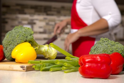raw vegetables placed on the kitchen table with a woman in the background