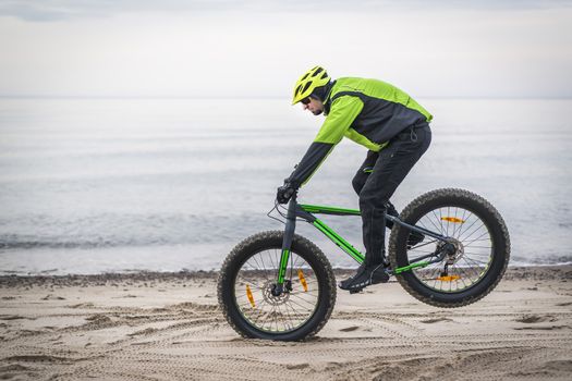 Young man on fat bike riding on the beach in february - Poland
