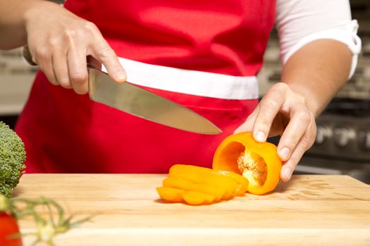 caucasian woman about to cut raw vegetables  on the kitchen