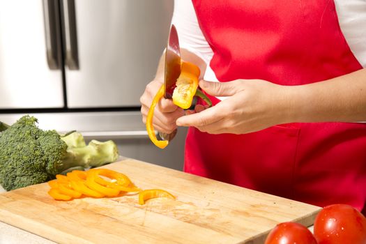 caucasian woman about to cut raw vegetables  on the kitchen