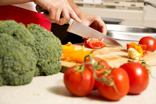 caucasian woman about to cut raw vegetables  on the kitchen