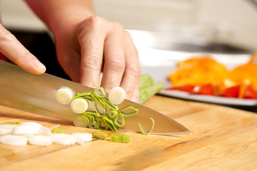 caucasian woman is cutting raw vegetables  on the kitchen table