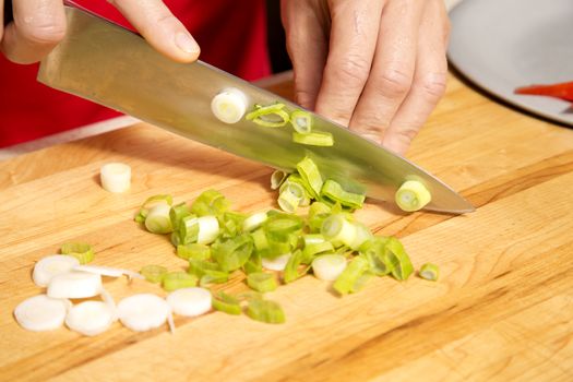 caucasian woman is cutting raw vegetables  on the kitchen table