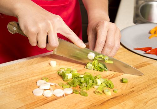 caucasian woman is cutting raw vegetables  on the kitchen table