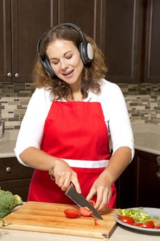 woman in the kitchen listening to music and cutting vegetables