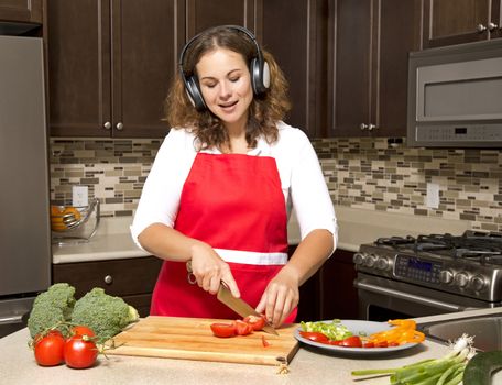 woman in the kitchen listening to music and cutting vegetables