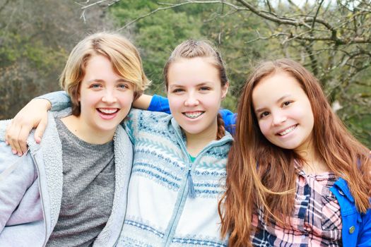 Three Girls Sitting together with green Trees in the Background