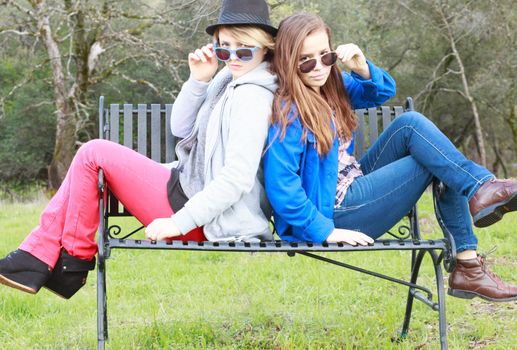 Two Girls Sitting on a Bench with Sunglasses