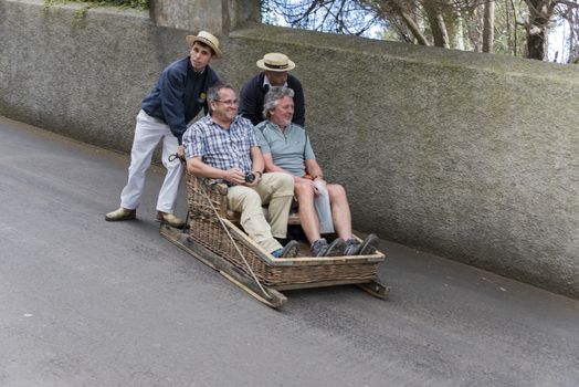 FUNCHAL,PORTUGAL-MARCH 19 Toboggan riders  dive with sledge with tourists on MArch 19, 2016 in Monte- Funchal, Portugal. This is done on public streets and is an old tradition only of this island