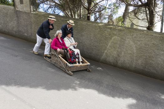 FUNCHAL,PORTUGAL-MARCH 19 Toboggan riders  dive with sledge with tourists on MArch 19, 2016 in Monte- Funchal, Portugal. This is done on public streets and is an old tradition only of this island