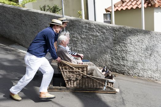 FUNCHAL,PORTUGAL-MARCH 19 Toboggan riders  dive with sledge with tourists on MArch 19, 2016 in Monte- Funchal, Portugal. This is done on public streets and is an old tradition only of this island