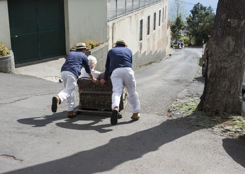 FUNCHAL,PORTUGAL-MARCH 19 Toboggan riders  dive with sledge with tourists on MArch 19, 2016 in Monte- Funchal, Portugal. This is done on public streets and is an old tradition only of this island