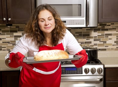 caucasian woman baking a bread in kitchen oven
