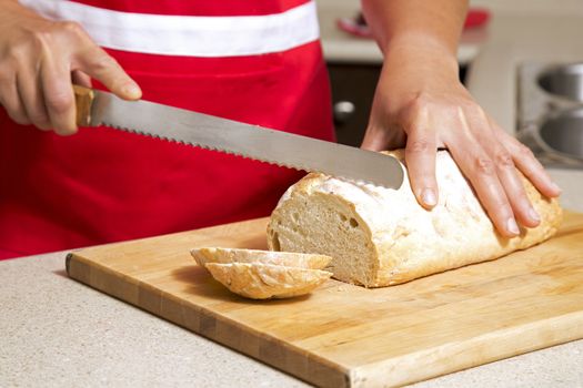 caucasian woman cutting a bread with knife in kitchen
