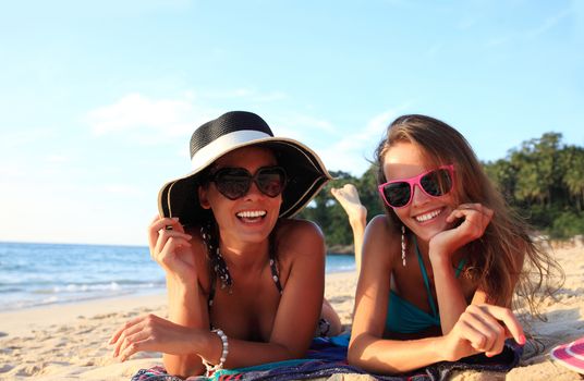 Happy smiling female friends lying on tropical beach