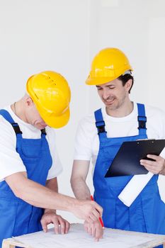 Team of builders with construction plan indoors