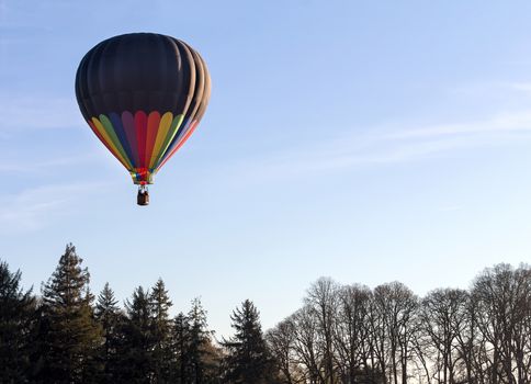 Colorful Hot Air Balloon Flying over landscape with trees