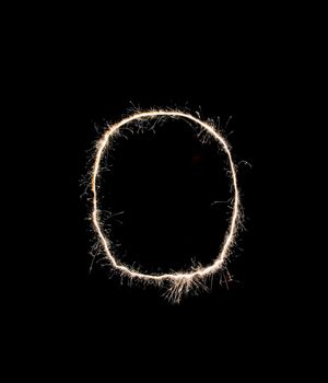 Letter O drew with spakrs on a black background.