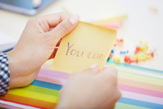 Human hand holding adhesive note with You can text