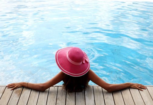 Beautiful woman relaxing at swimming pool at tourist resort