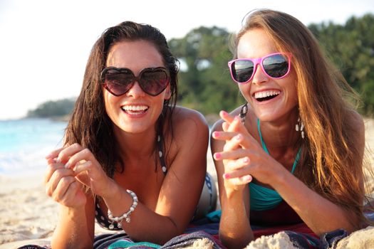 Happy smiling female friends lying on tropical beach