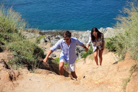 Young couple hiking on the hill near sea