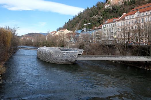 An artificial island on the Mur river. It is a famous landmark and called Murinsel - designed from American architect Vito Acconci and built for the European Cultural Capital 2003 activities now a cafe.