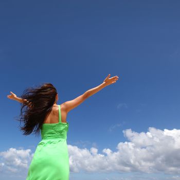 Woman with raised hands over blue sky background