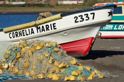 Colourful fishing boat and fishing nets on the beach in the small fishing village of Curanipe in the Maule Region of Chile.