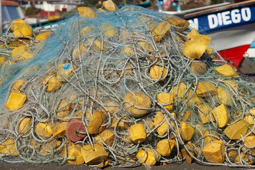 Fishing nets piled on the beach next to a colourful fishing boat in the small fishing village of Curanipe in the Maule Region of Chile.