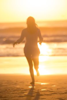 Happy woman enjoying isummer, running joyfully on beach in sunset.