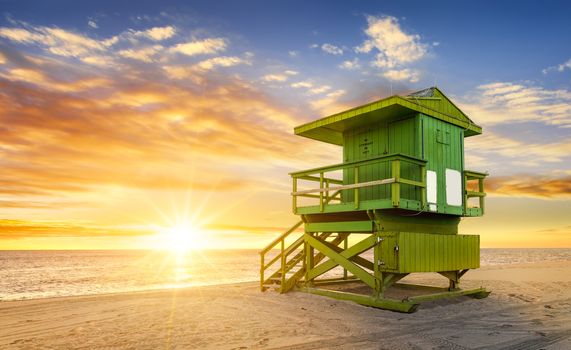 Miami South Beach sunrise with lifeguard tower and coastline with colorful cloud and blue sky.