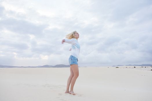 Relaxed woman enjoying freedom feeling happy at beach in the morning. Serene relaxing woman in pure happiness and elated enjoyment with arms outstretched.